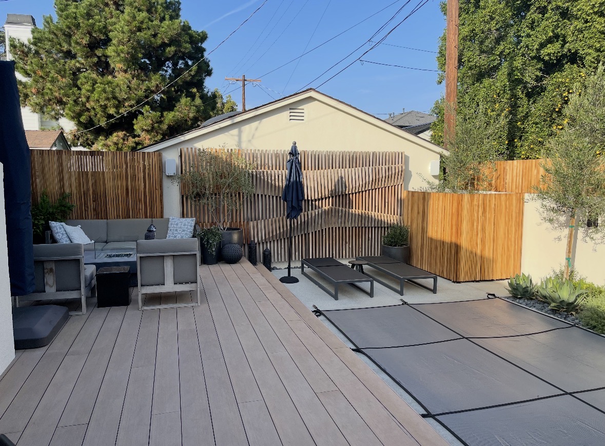 Backyard patio with a wood slat privacy screen beside a pool