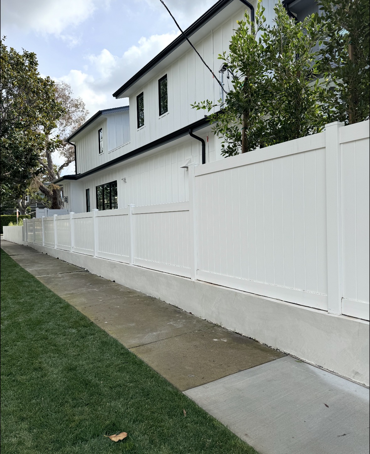 White vinyl fence and matching gate beside a sidewalk