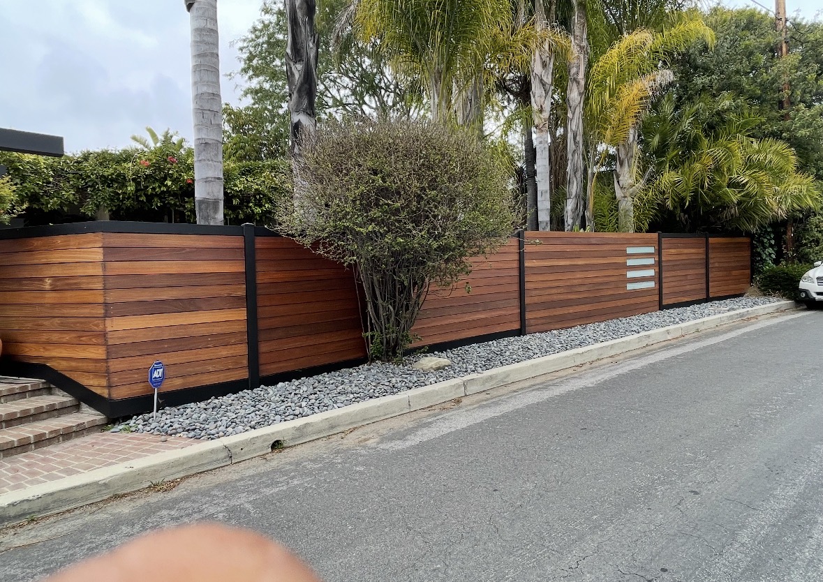 Long hardwood horizontal fence beside a landscaped street