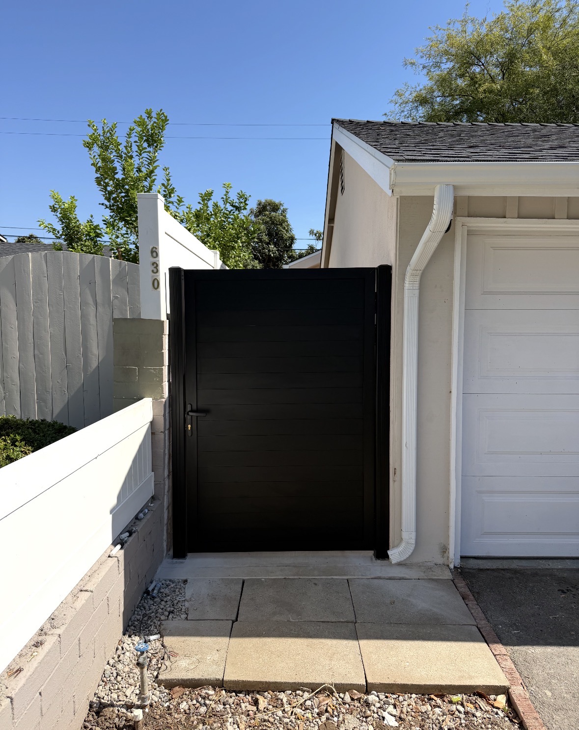 Black horizontal slat gate beside a garage