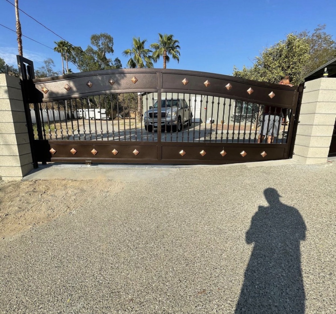 Dark bronze arched double driveway gate with copper accents
