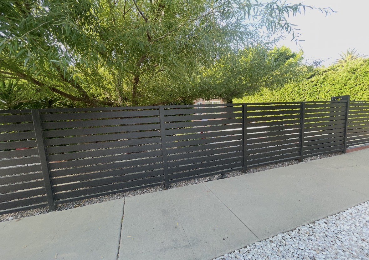 Dark horizontal slat fence along a garden walkway