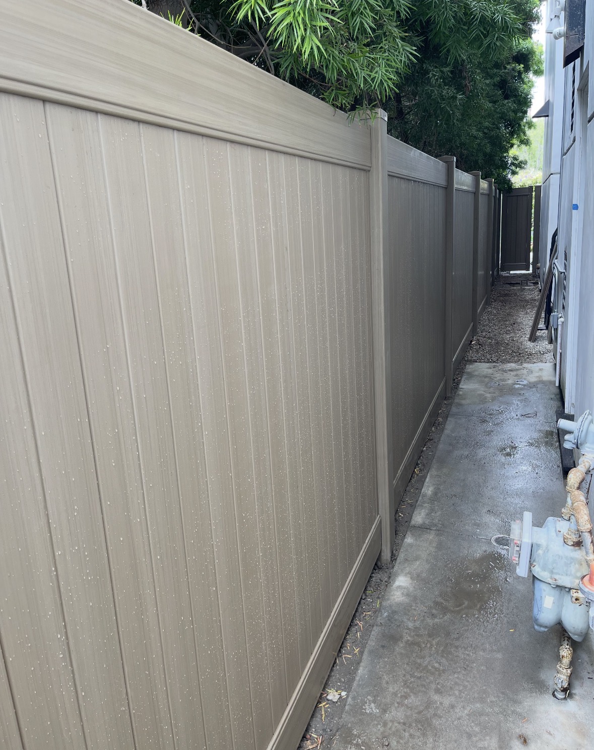 Tan vinyl privacy fence along a narrow side walkway