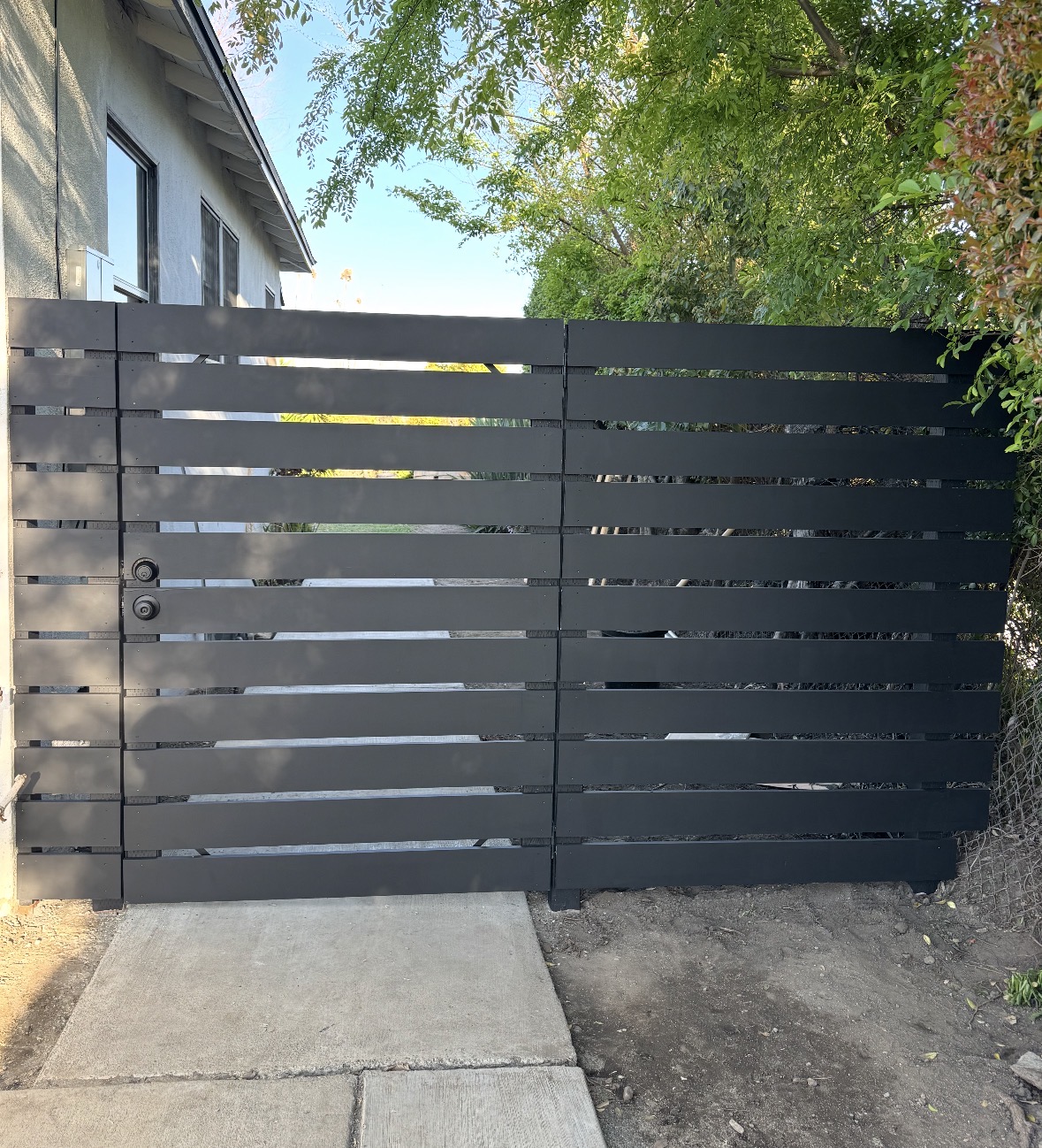 Black horizontal slat gate beside a landscaped path