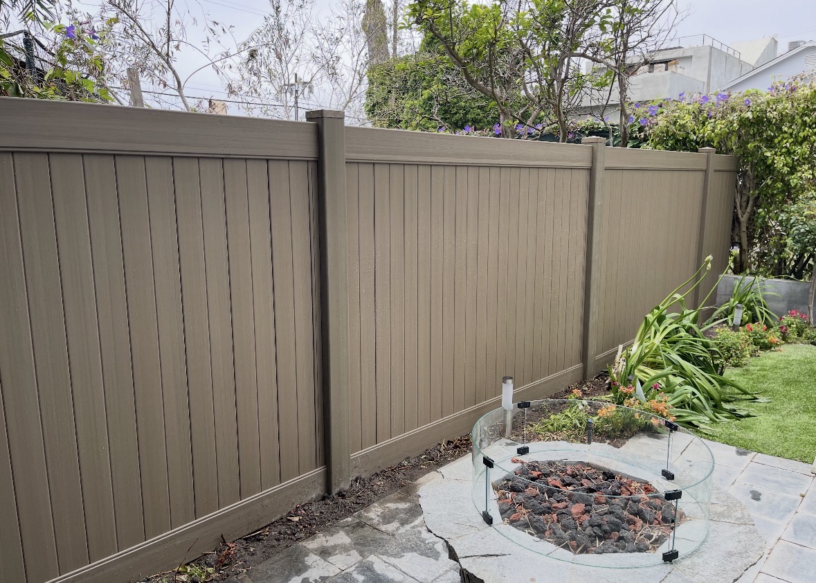 Tan vinyl privacy fence around a backyard fire pit