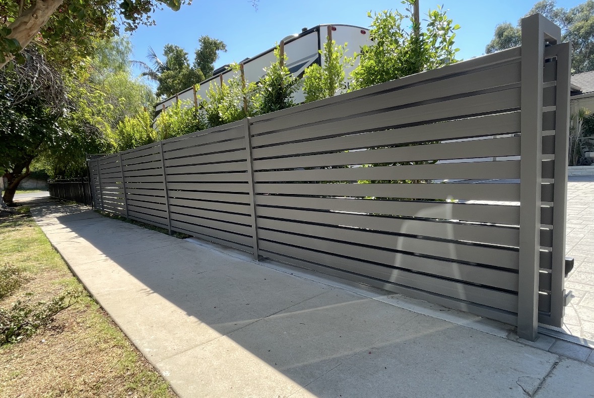 Grey horizontal slat sliding gate along a walkway