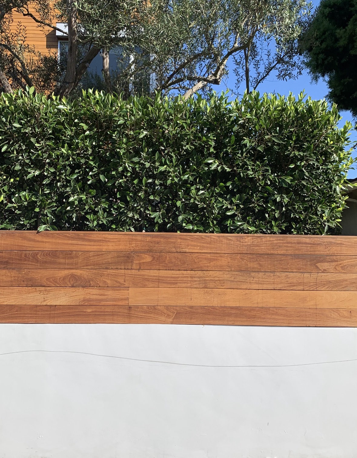 Horizontal wood fencing above a white wall