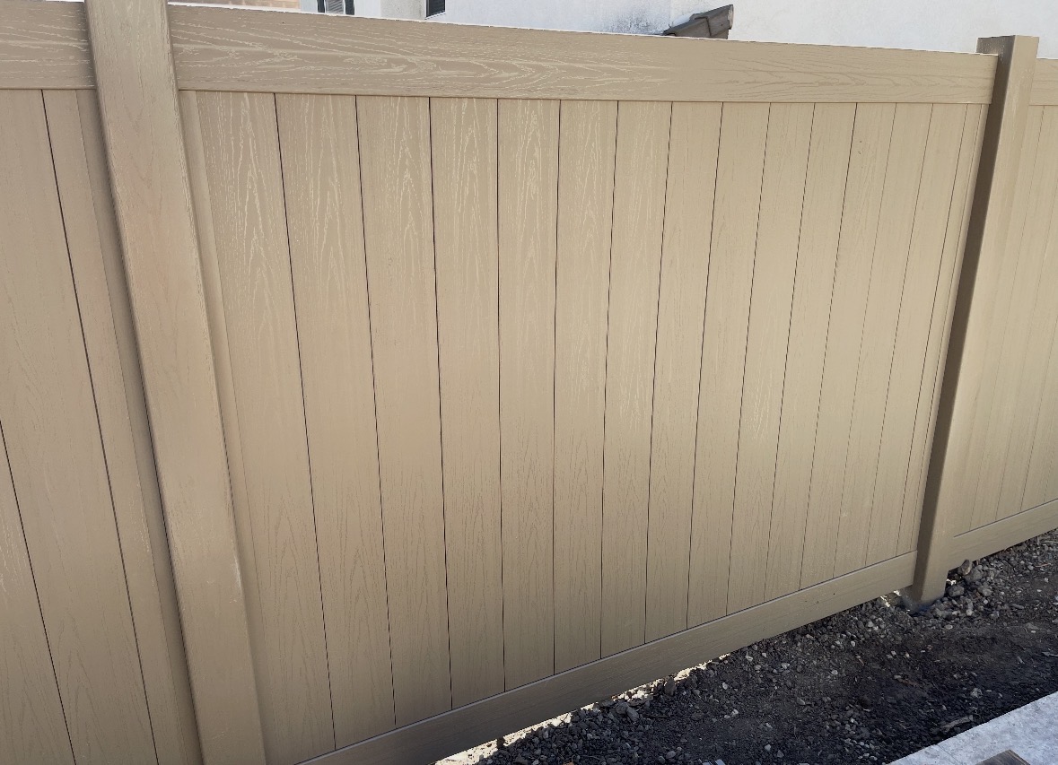 Tan vinyl fence panels with a woodgrain texture
