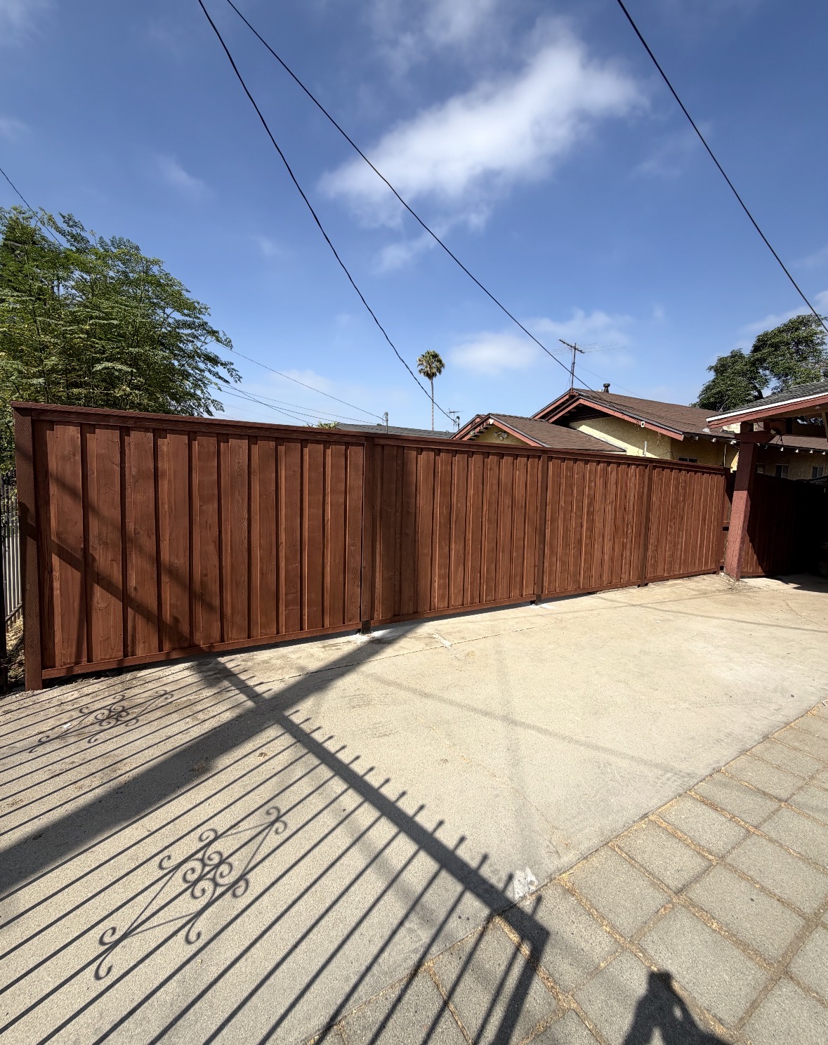 New wood fence across a sunny driveway