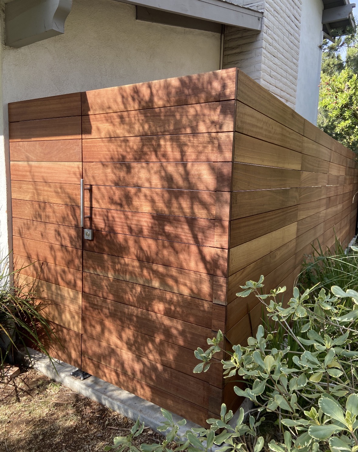 Hardwood horizontal slat gate in a landscaped corner